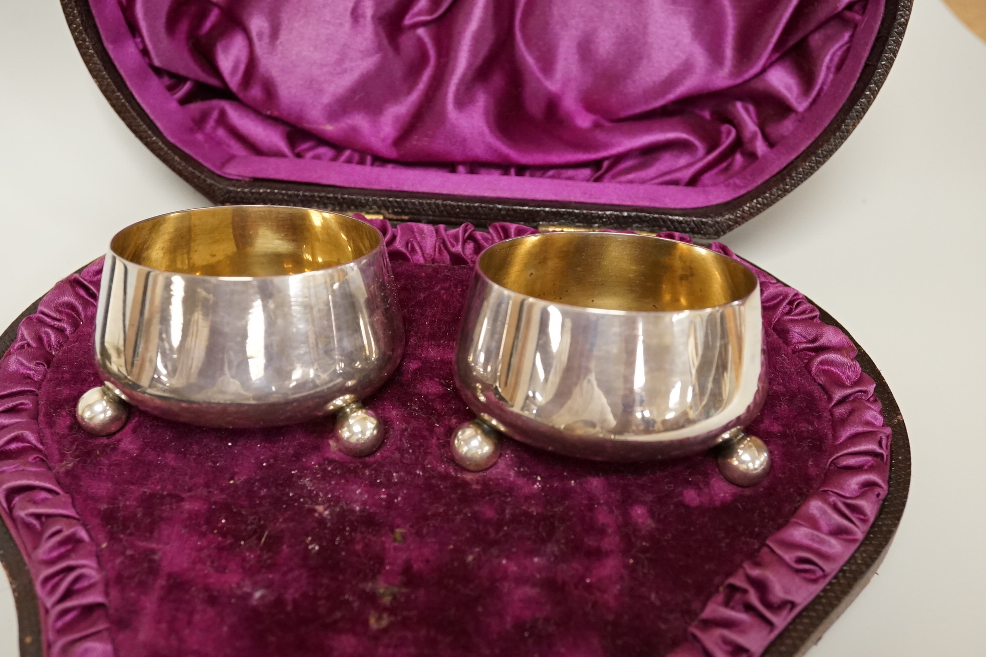 A cased pair of Victorian silver circular salts, by Edward Hutton, London, 1886, lacking spoons, together with a cased set of six silver bean end coffee spoons, a cased silver spoon, a small silver 'Dunlop Golf Ball Hole